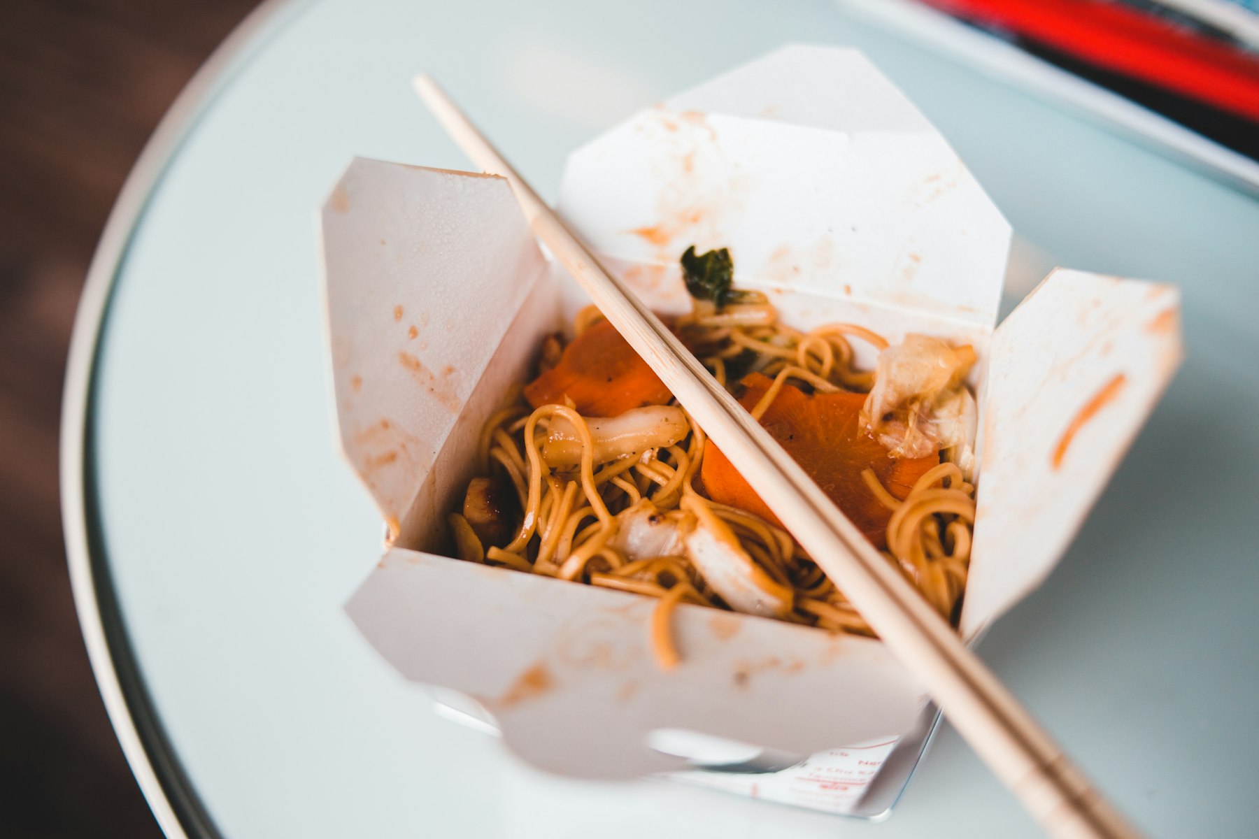 Noodles in a Chinese takeout box with chopsticks